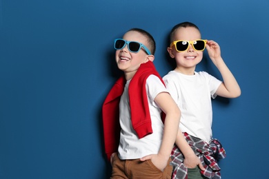 Photo of Portrait of cute twin brothers with sunglasses on color background. Space for text