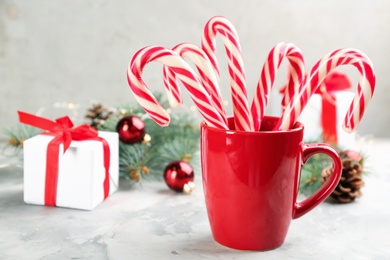 Photo of Many sweet candy canes, gift box and Christmas decor on light table. Space for text