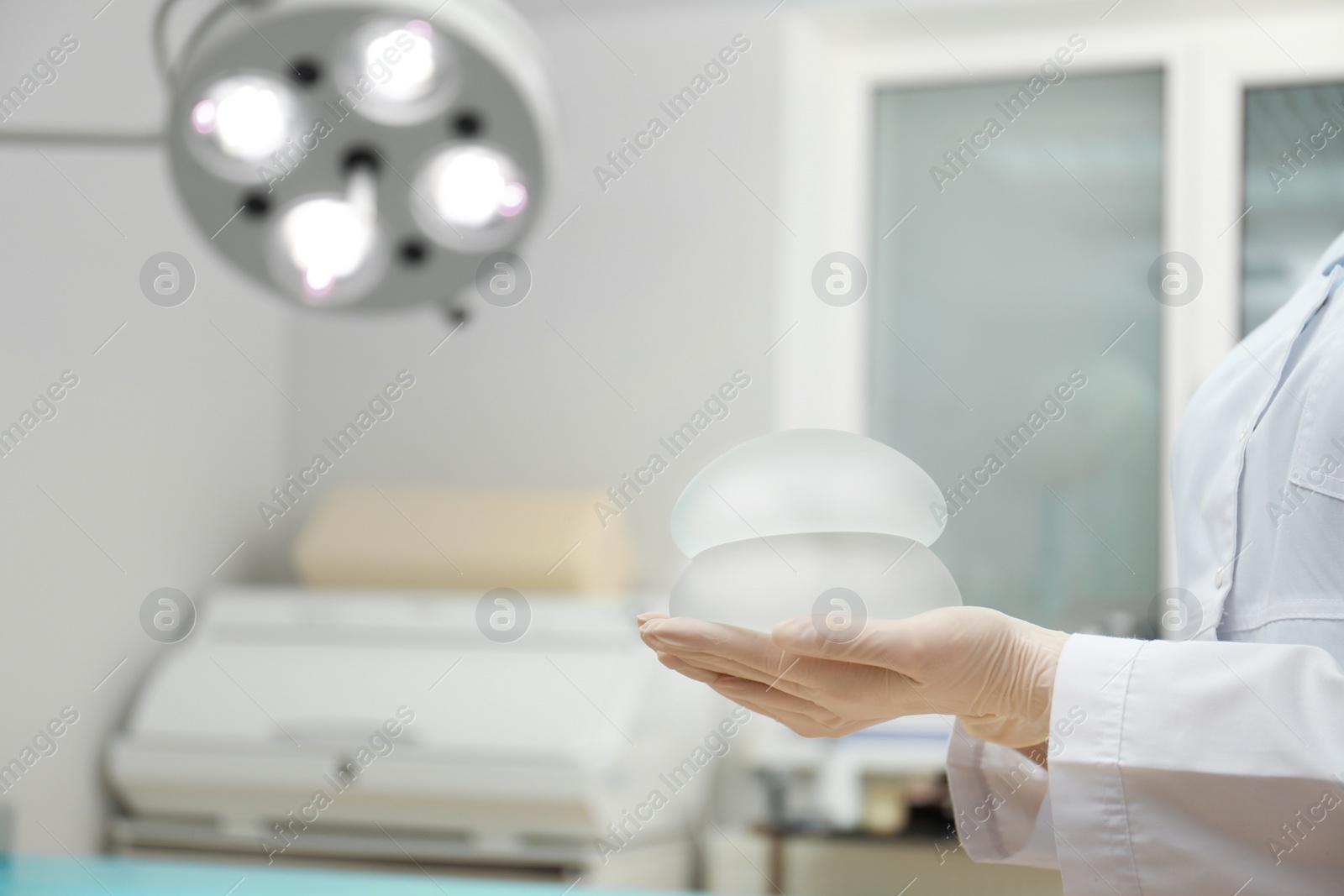 Photo of Doctor holding silicone implants for breast augmentation in clinic, space for text. Cosmetic surgery