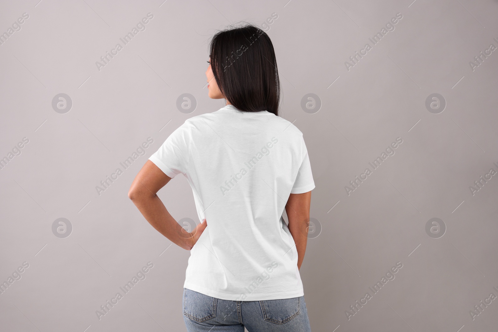 Photo of Woman wearing white t-shirt on light grey background, back view