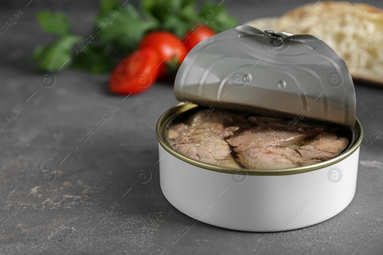 Photo of Open tin can of tasty cod liver on grey table, closeup. Space for text