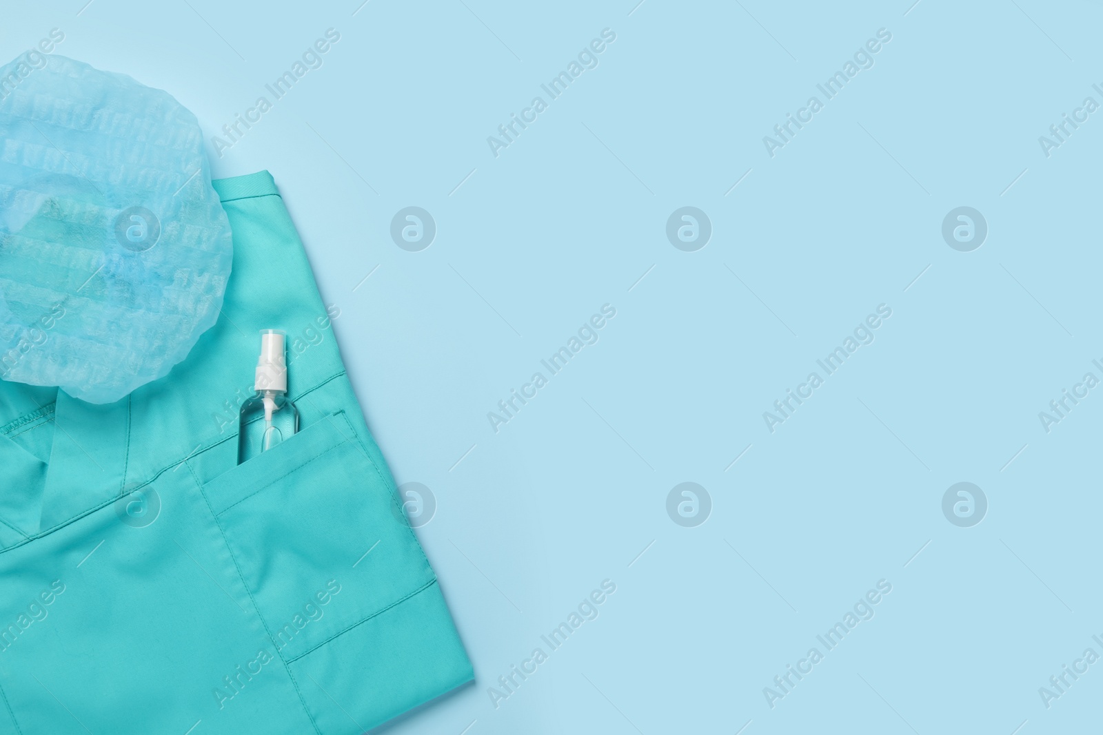 Photo of Medical uniform, cap and antiseptic on light blue background, flat lay. Space for text