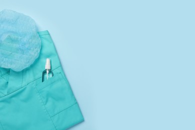 Photo of Medical uniform, cap and antiseptic on light blue background, flat lay. Space for text
