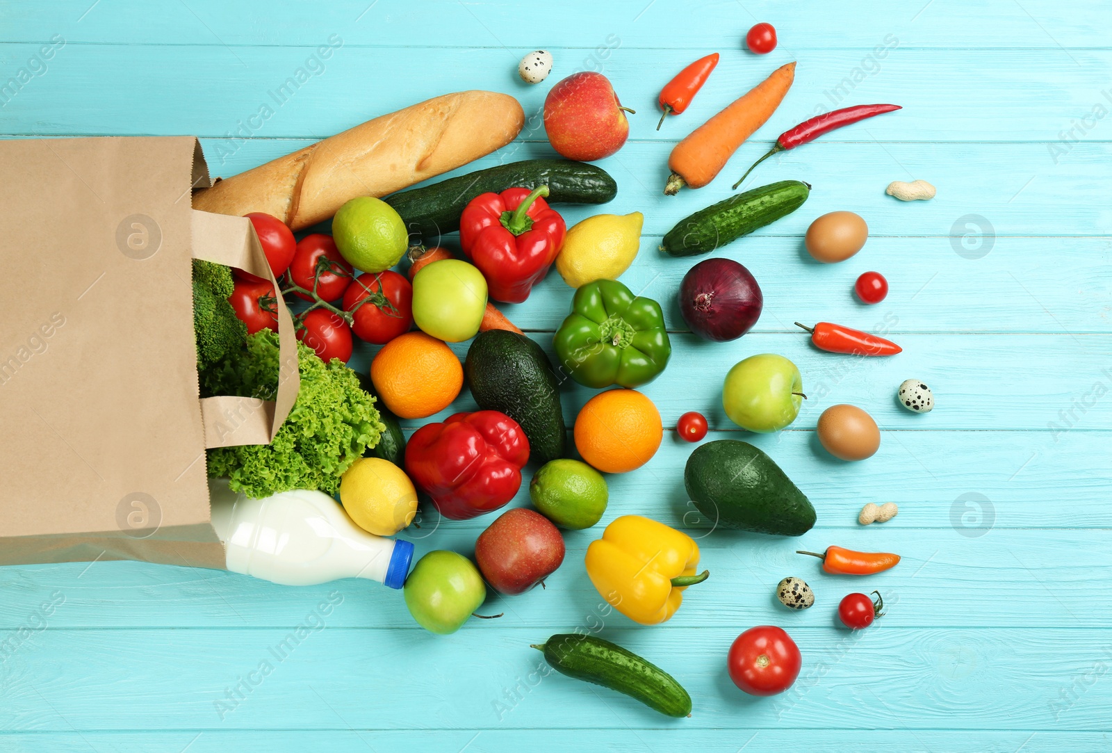 Photo of Flat lay composition with overturned paper bag and groceries on blue wooden background