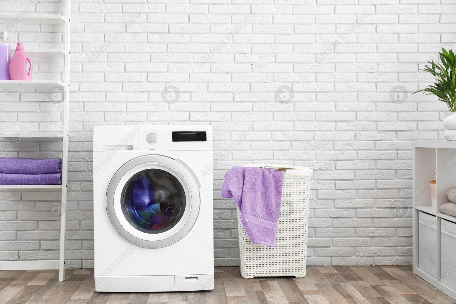 Photo of Modern washing machine near brick wall in laundry room interior, space for text