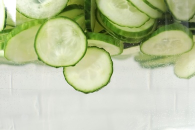 Photo of Fresh water with cucumber slices on light background, closeup