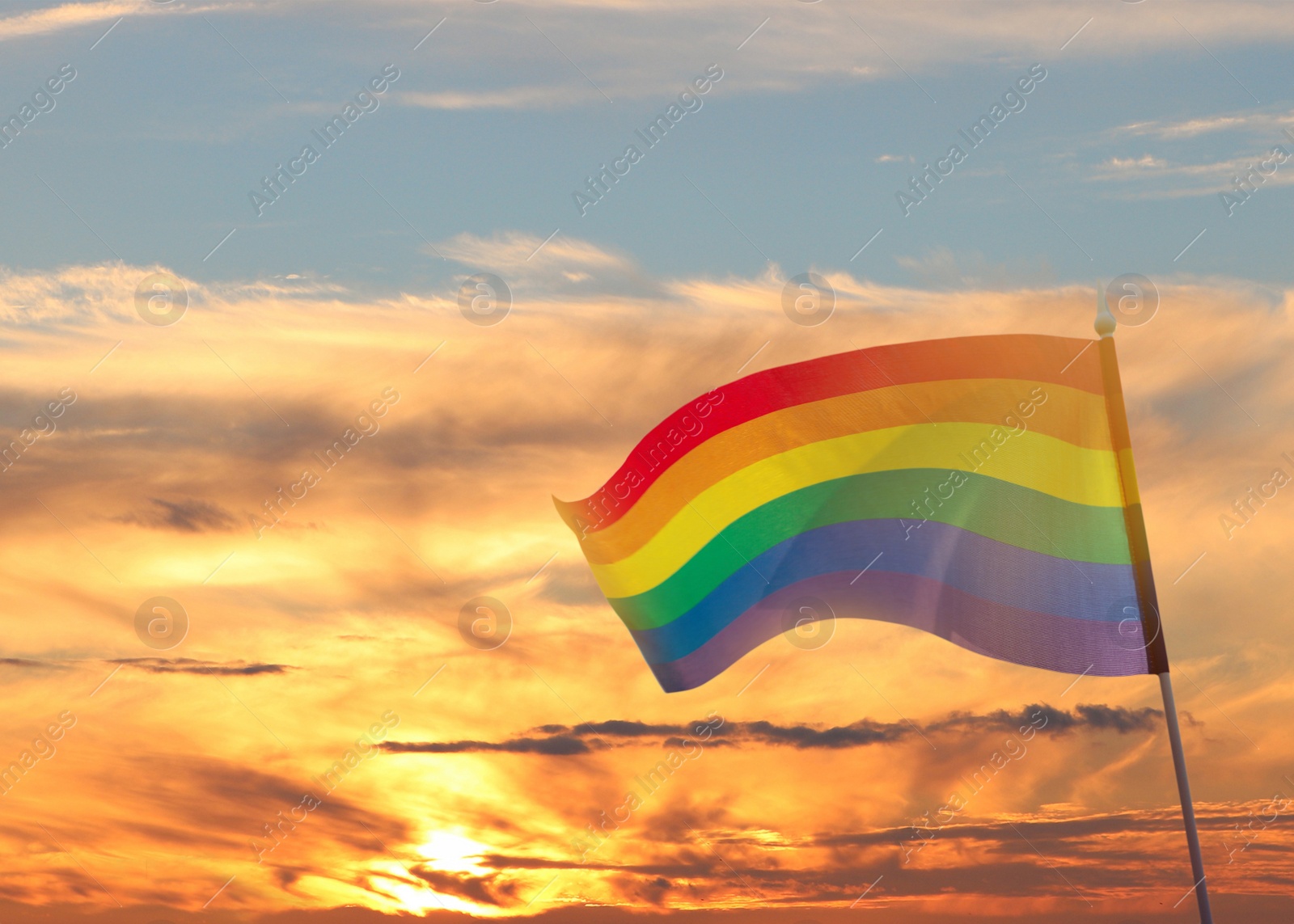 Image of Bright rainbow LGBT flag against sky at sunset