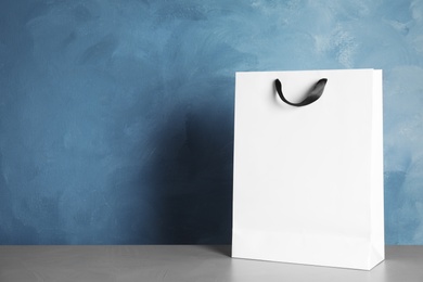 Paper shopping bag on table against color background. Mock up for design