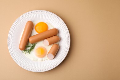 Photo of Delicious boiled sausages, fried eggs and dill on beige background, top view. Space for text