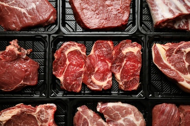 Photo of Plastic containers with fresh raw meat as background, top view