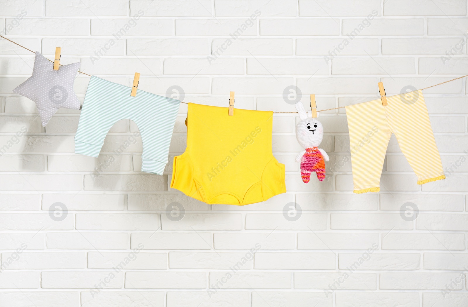 Photo of Baby clothes hanging on washing line near white brick wall