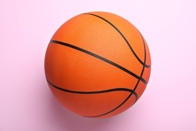 Orange ball on pink background, top view. Basketball equipment