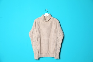 Hanger with stylish sweater on color background