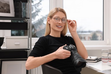 Photo of Professional photographer with digital camera at table in office