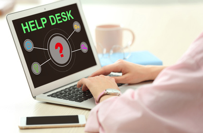 Image of Young woman using laptop at table indoors, closeup. Help desk service