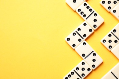 Classic domino tiles on yellow background, flat lay. Space for text