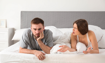 Photo of Young couple quarreling in bedroom. Relationship problems