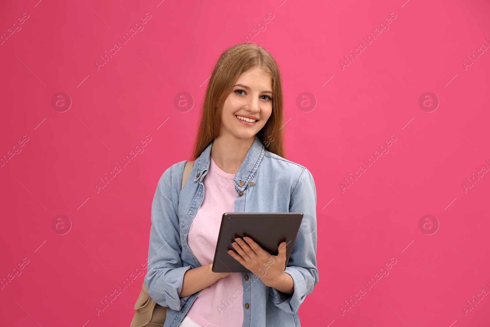 Photo of Teenage student with tablet and backpack on pink background