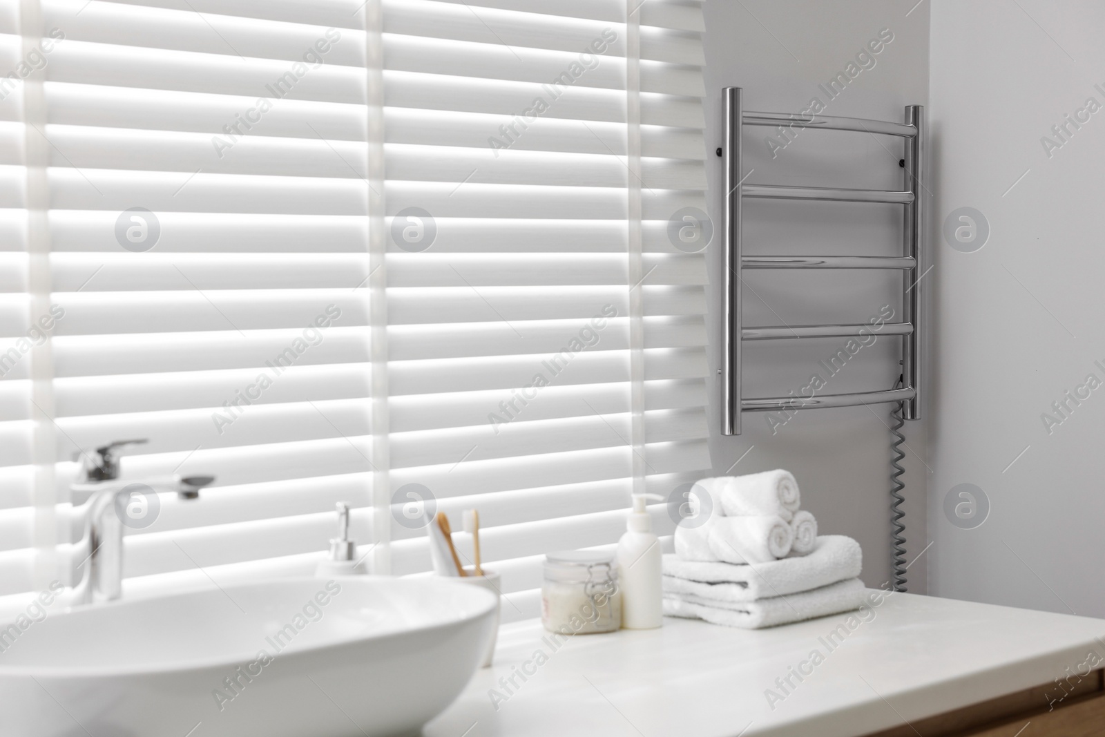 Photo of Heated towel rail on white wall in bathroom