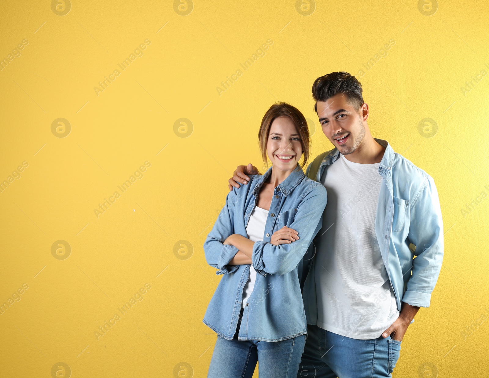 Photo of Young couple in stylish clothes on color background. T-shirts as mockup for design