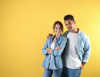 Photo of Young couple in stylish clothes on color background. T-shirts as mockup for design