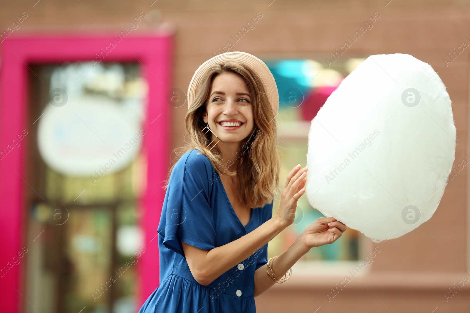 Photo of Happy young woman with cotton candy outdoors