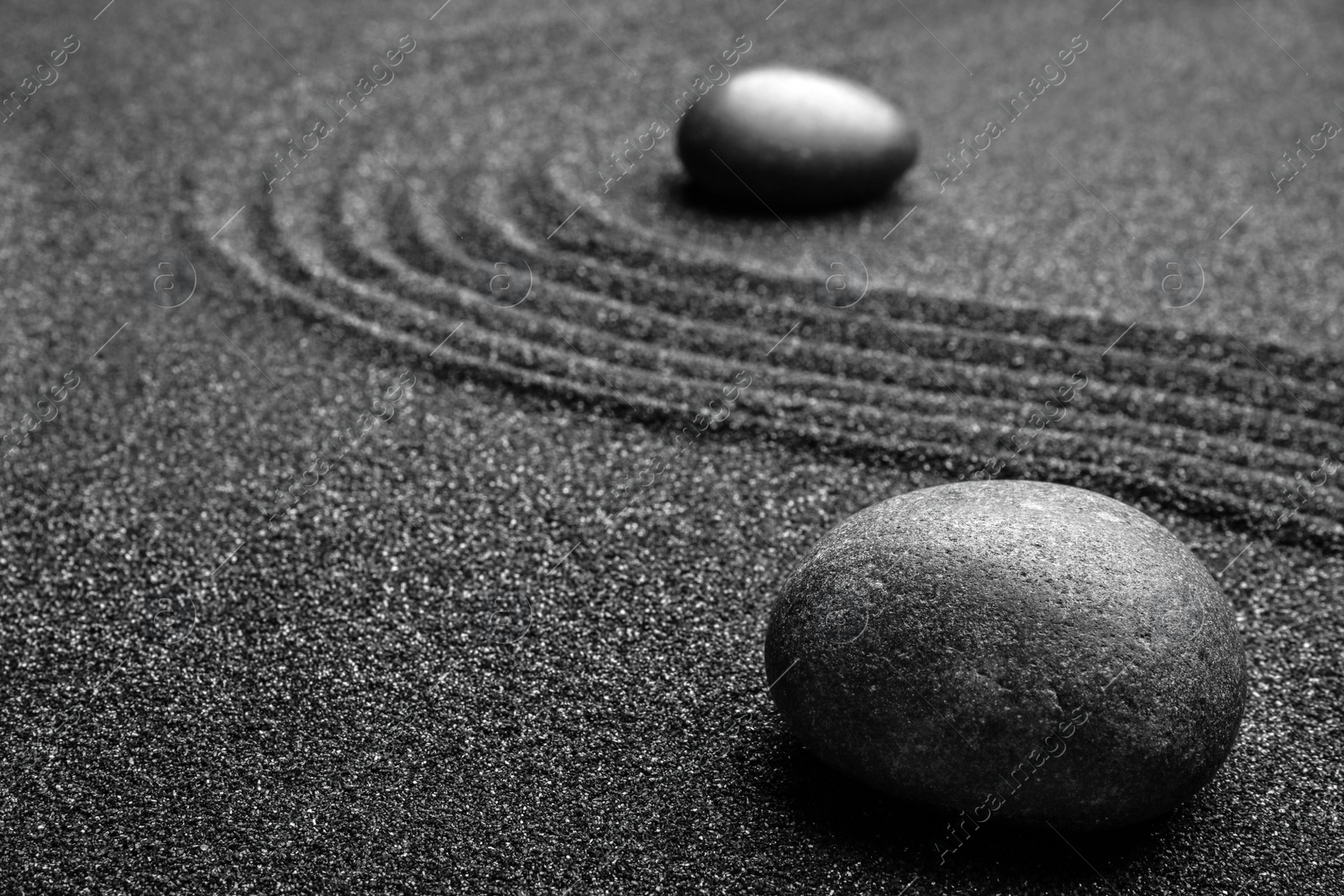 Photo of Black sand with stones and beautiful pattern. Zen concept