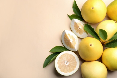 Photo of Fresh cut and whole pomelo fruits with leaves on beige background, flat lay. Space for text