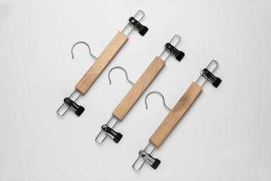 Empty wooden hangers with clips on light grey background, flat lay