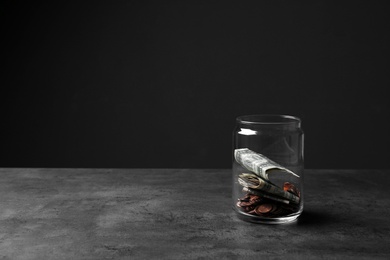 Photo of Donation jar with money on table against dark background. Space for text