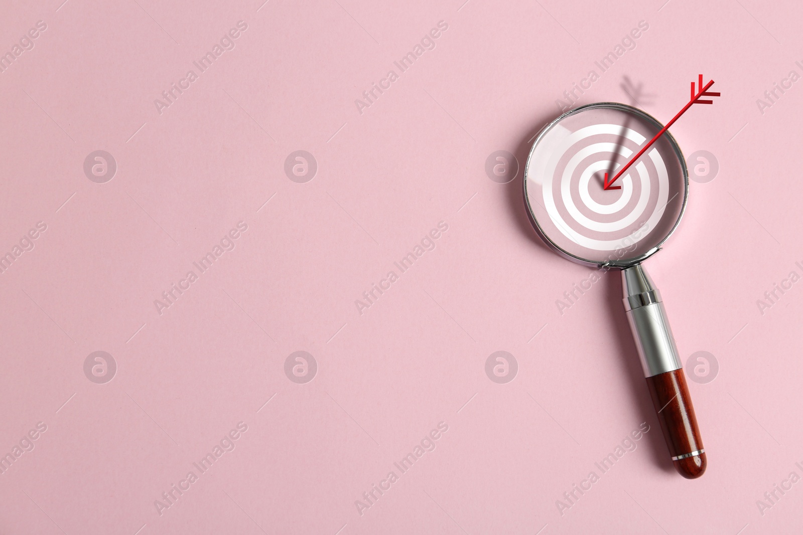 Image of Magnifying glass with illustration of target and arrow on pink background, top view. Space for text