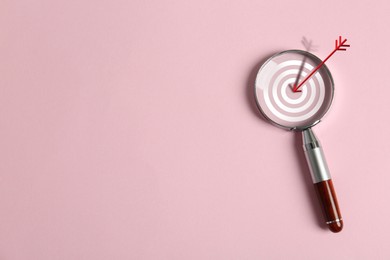 Image of Magnifying glass with illustration of target and arrow on pink background, top view. Space for text