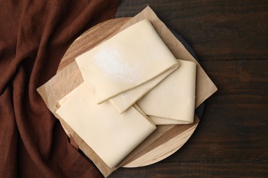 Photo of Raw puff pastry dough on wooden table, top view