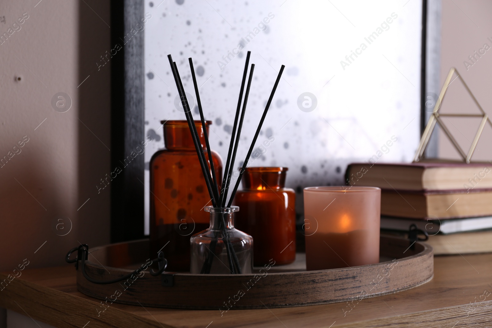 Photo of Wooden tray with air reed freshener and candles on table indoors