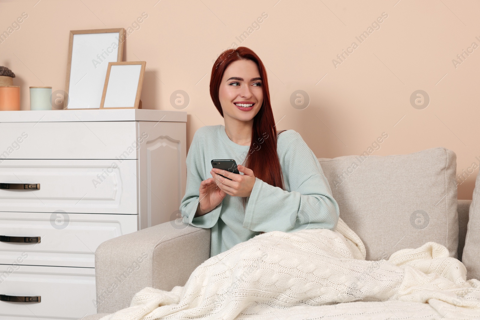 Photo of Happy woman with red dyed hair using smartphone at home