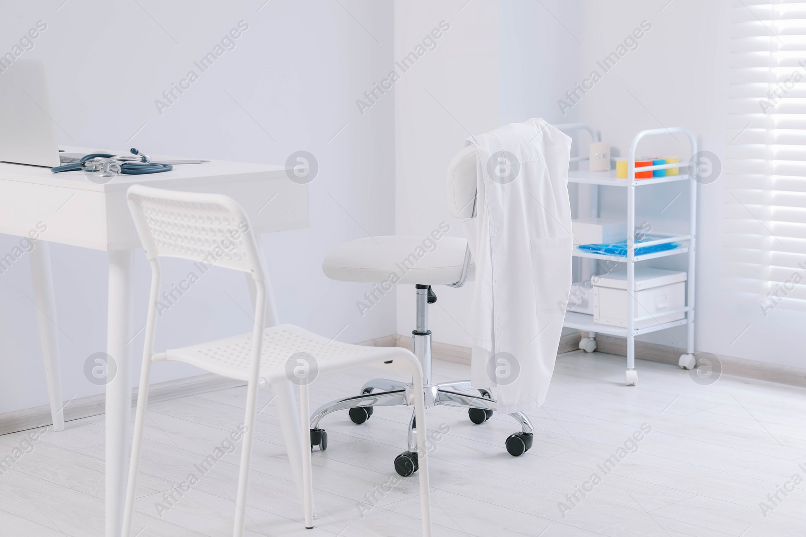 Photo of White doctor's gown hanging on chair in clinic