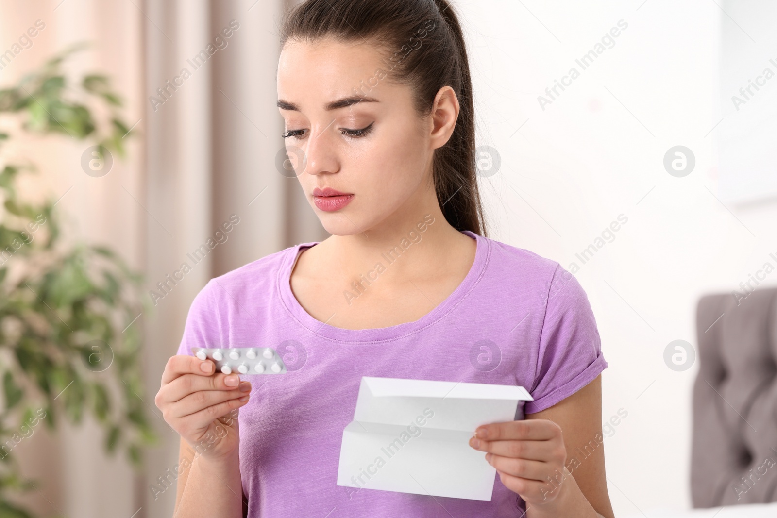 Photo of Beautiful young woman with pills at home