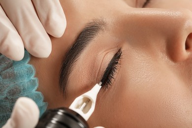 Photo of Young woman undergoing procedure of permanent eyeliner makeup, closeup