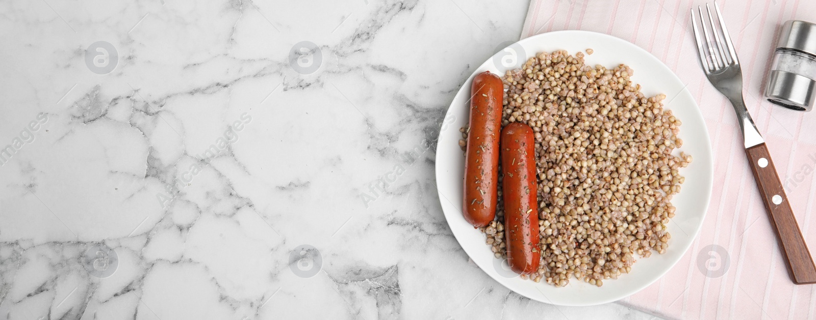 Image of Tasty buckwheat porridge and sausages on white marble table, flat lay with space for text. Banner design