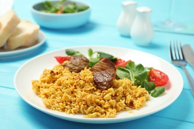 Plate of tasty rice pilaf with meat served on table