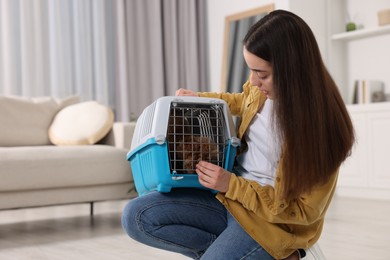 Travel with pet. Woman holding carrier with dog at home