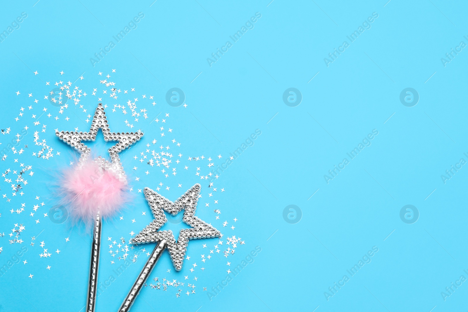 Photo of Beautiful silver magic wands and confetti on light blue background, flat lay. Space for text