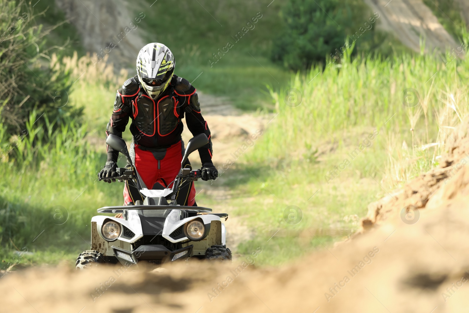 Photo of Man driving modern quad bike on sandy road. Extreme sport