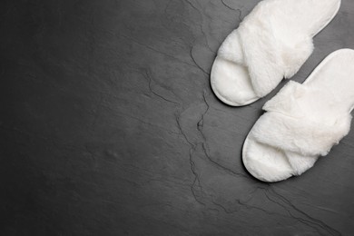 Photo of Pair of soft slippers on dark grey floor, top view. Space for text