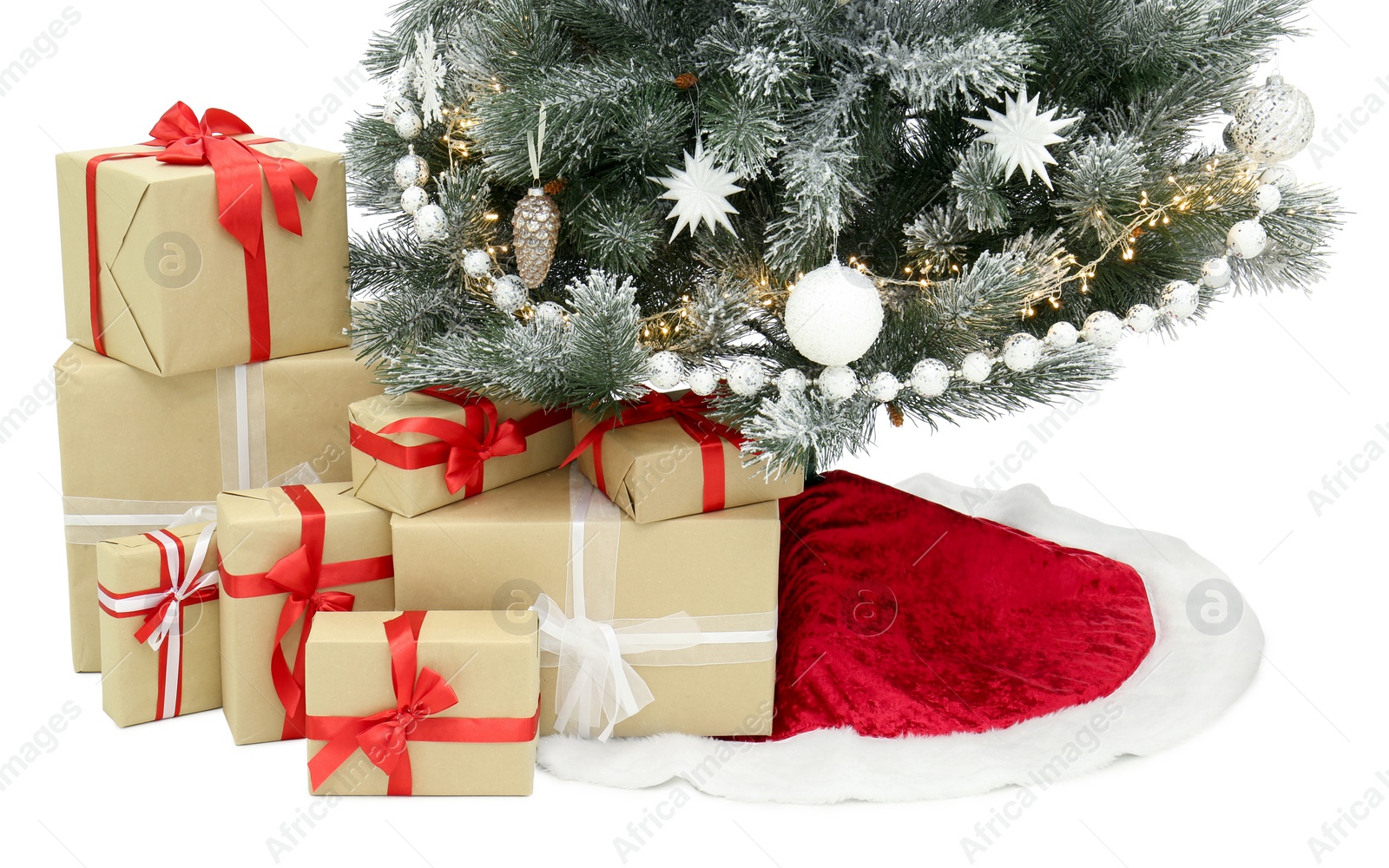 Photo of Decorated Christmas tree with red skirt and gift boxes on white background