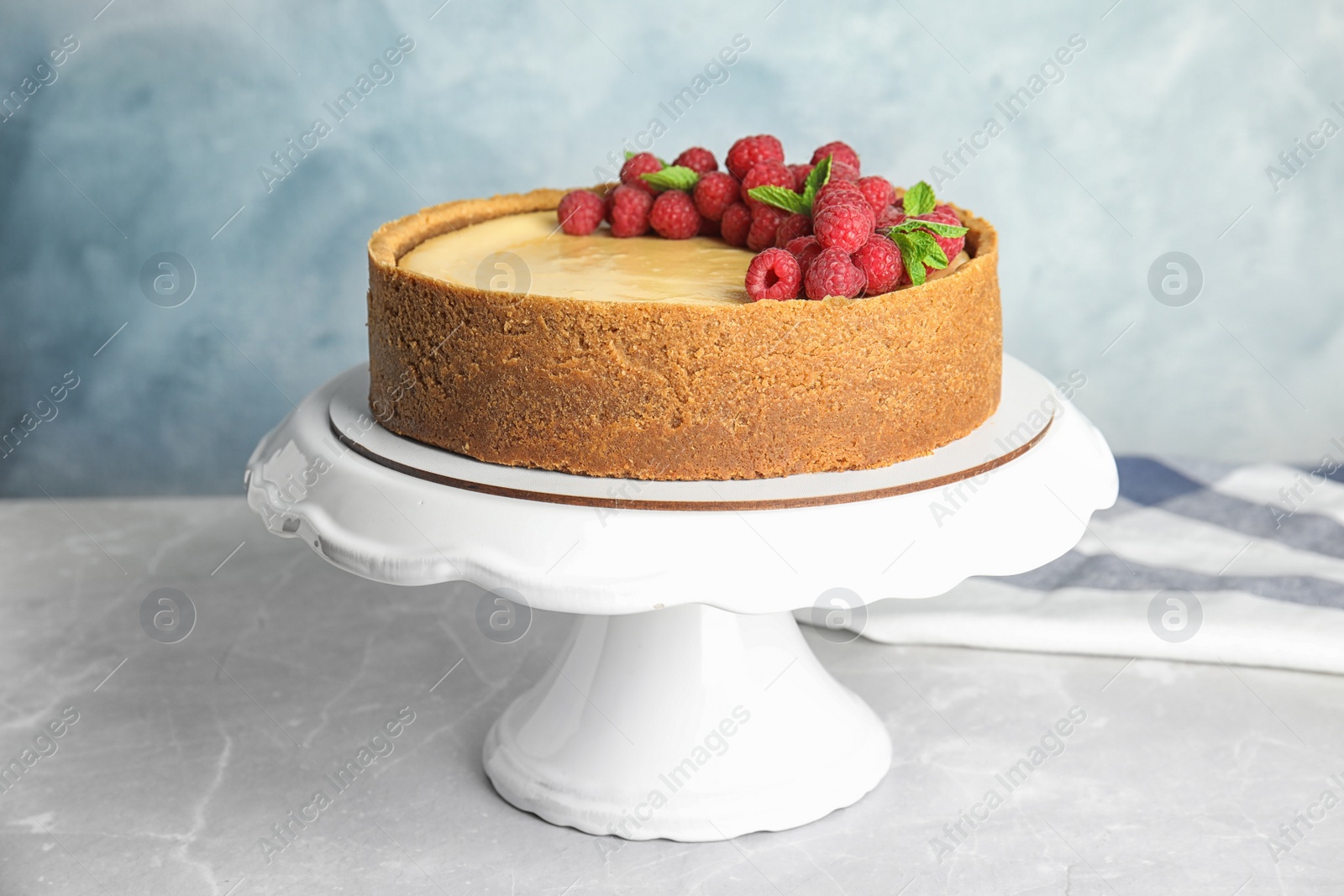 Photo of Dessert stand with delicious raspberry cake on table against blue background