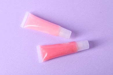 Photo of Different lip balms on lilac background, flat lay