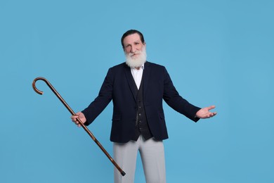 Senior man with walking cane on light blue background