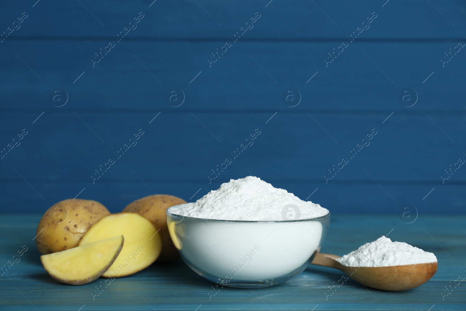 Photo of Starch and fresh raw potatoes on light blue wooden table. Space for text