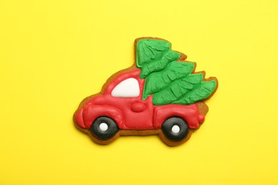 Photo of Christmas cookie in shape of car with fir tree on yellow background, top view